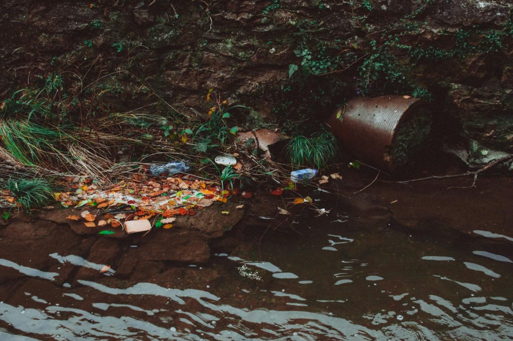 A riverbank littered with trash, highlighting environmental pollution and the need for recycling efforts.