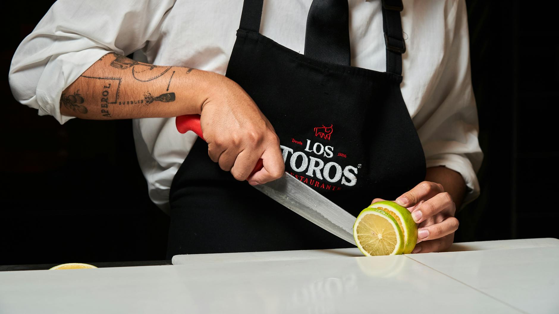 Chef skillfully slices a lemon in a professional kitchen setting.