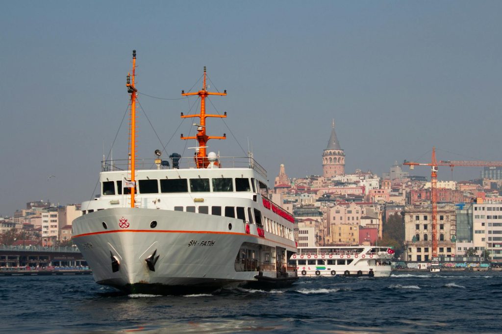 Ferry navigating the Bosphorus with the iconic Galata Tower in the background, Istanbul.