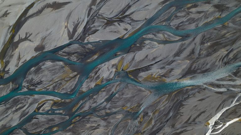 Aerial view of river branches over sandbanks creating natural abstract patterns in earthy tones.