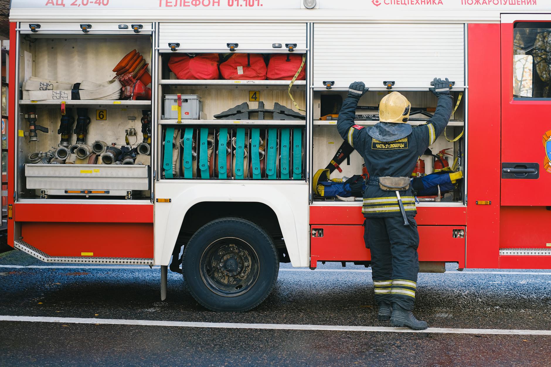 A dedicated firefighter organizing essential equipment on the side of a fire truck.