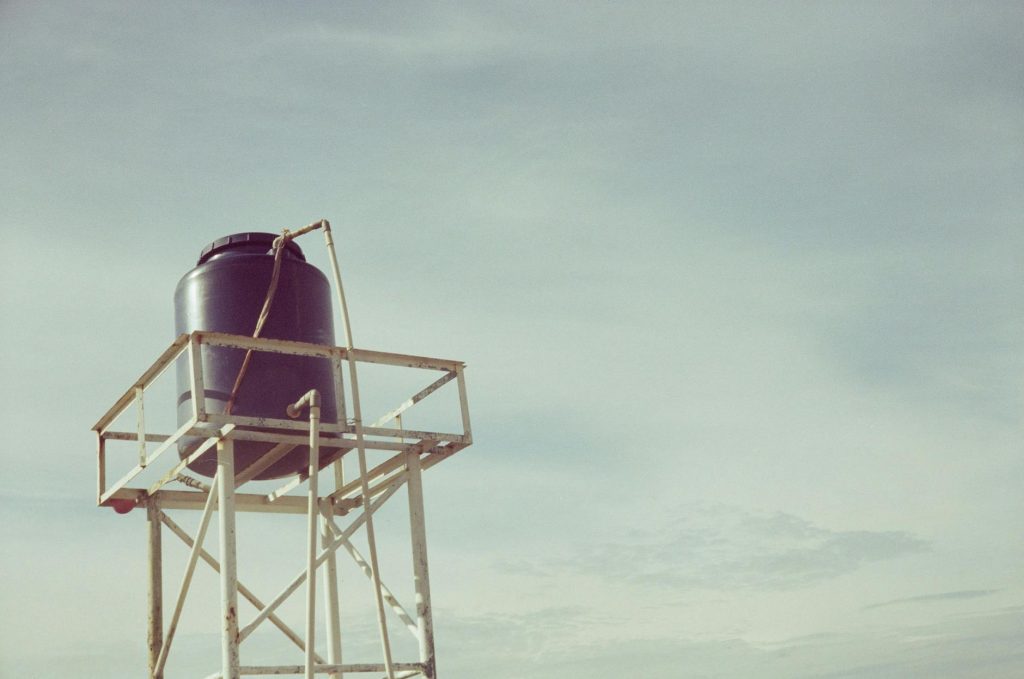 An industrial water tank atop a metal frame against a clear sky, showcasing infrastructure design.