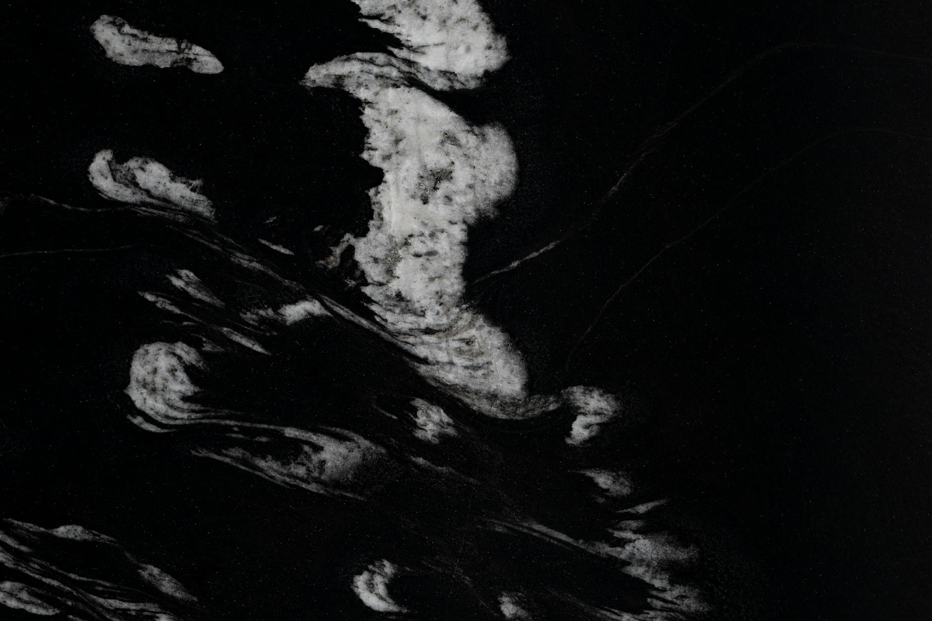 Dark abstract pattern with white streaks on marble background.
