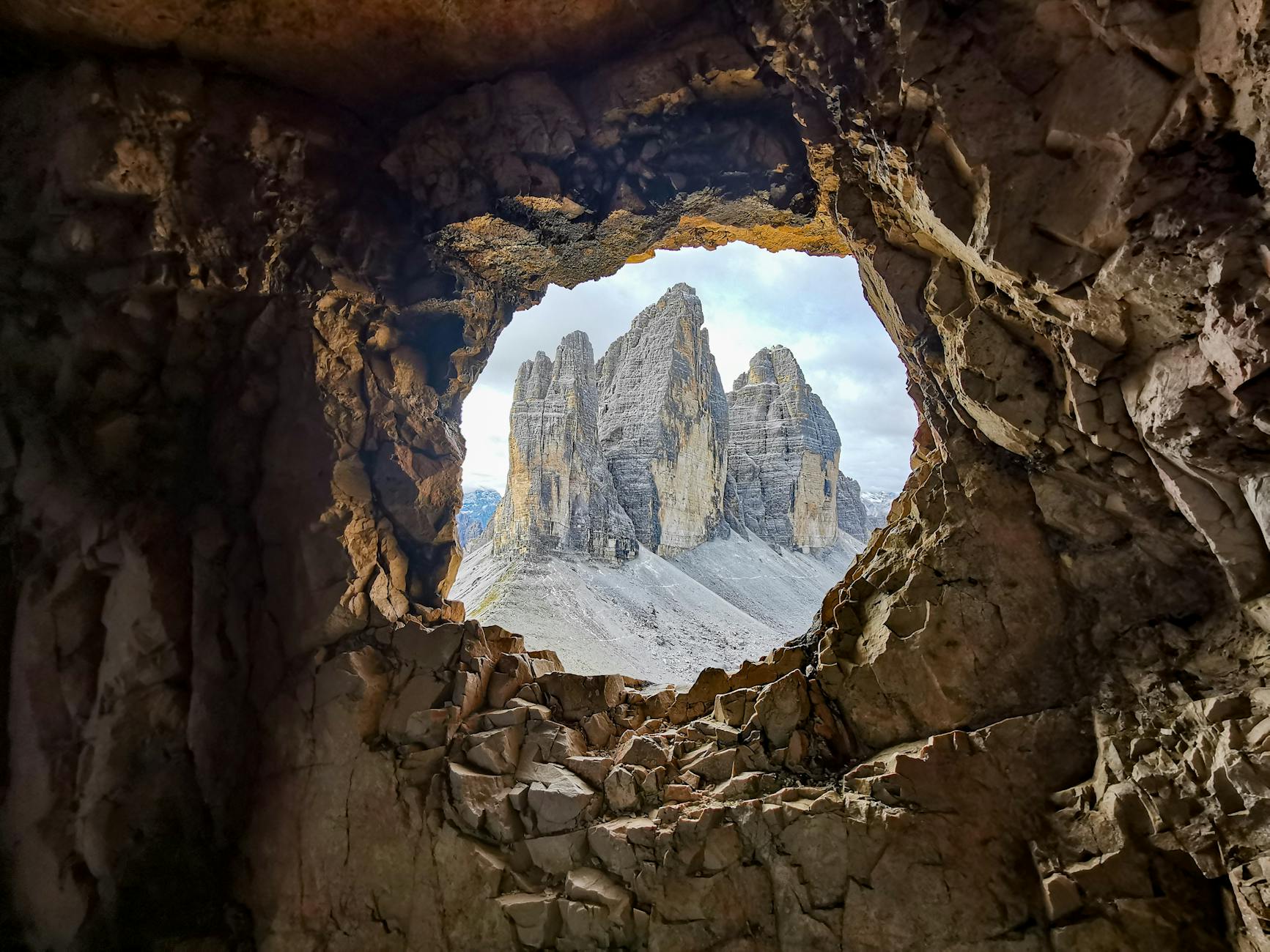 A breathtaking view of the Dolomites seen through a natural cave opening.