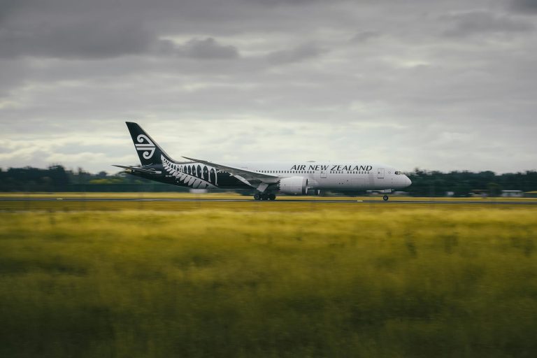 Air New Zealand Boeing 787 landing on a runway amidst New Zealand's scenic landscape.