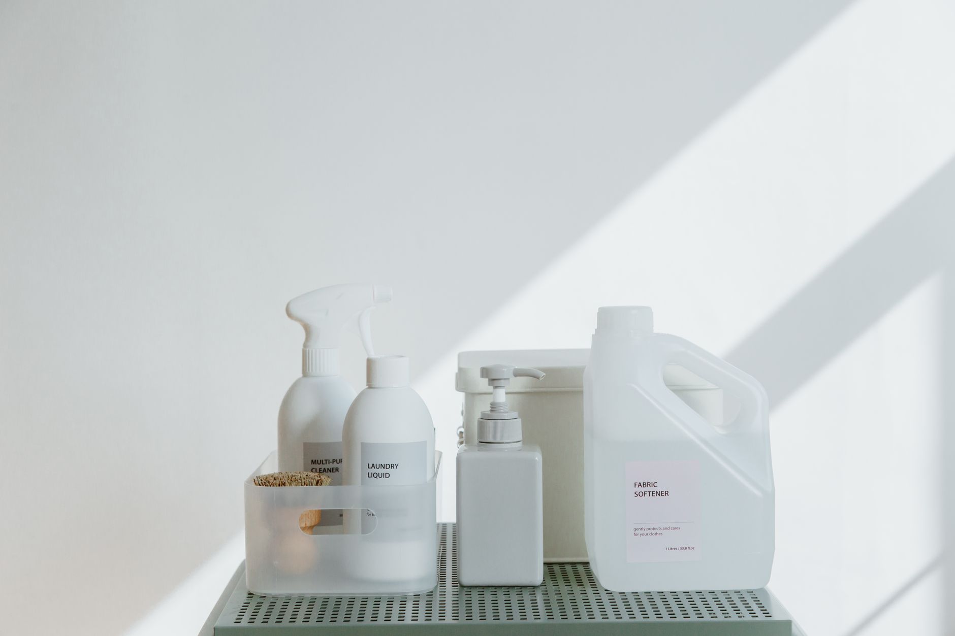 Clean and simple display of various cleaning products in soft lighting on a white background.